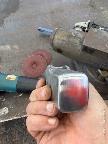 A face-on view of the hammer head. The edges and corners of the face have been rounded, and the face is polished